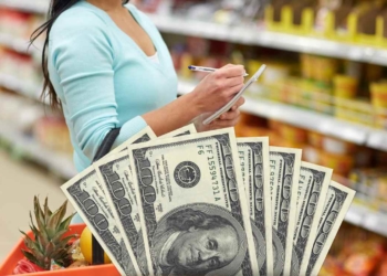 Woman grocery shopping and dollars to talk about changes in the Food Stamps program that affect SNAP beneficiaries