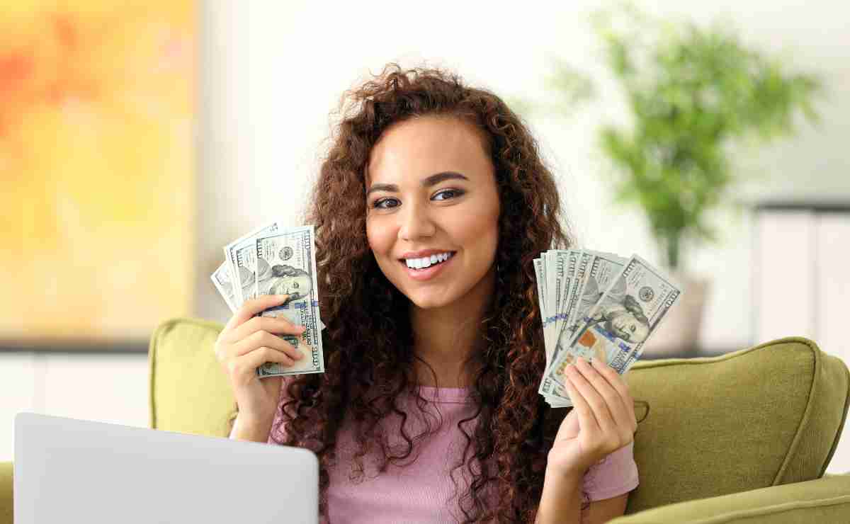 Woman with dollars smiling to talk about Social Security disability benefits in November