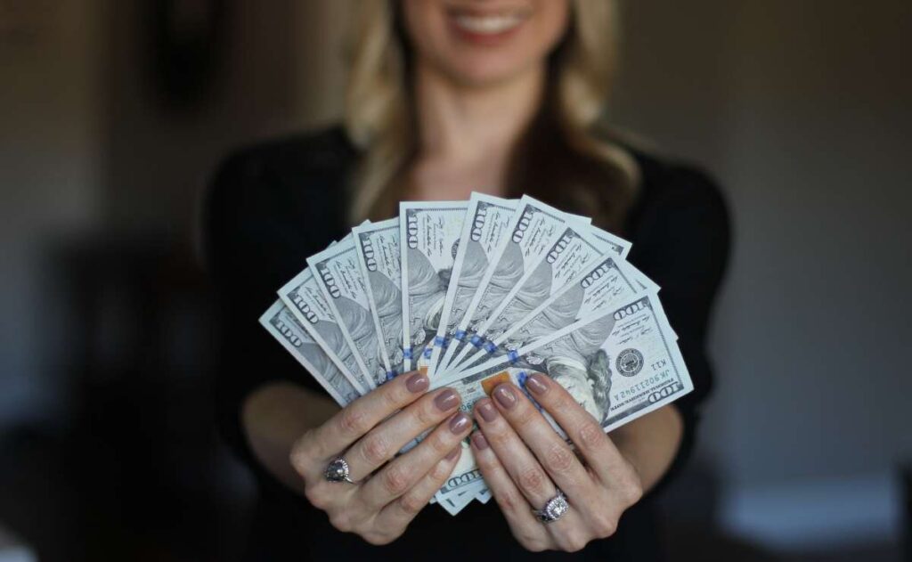 Woman showing dollars to talk about SNAP payment of up to $3,500 in November to some eligible Food Stamp beneficiaries