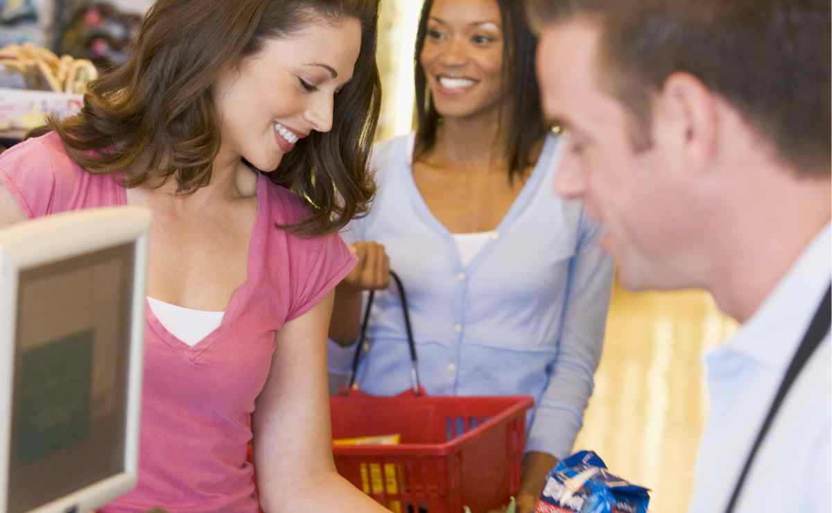 Women paying at a store with a cashier at the checkout to save using SNAP EBT cards at authorized grocery stores