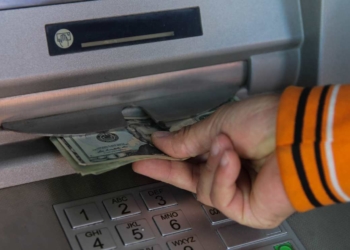 Hand with dollars at ATM for Social Security and SSDI amounts for 2024