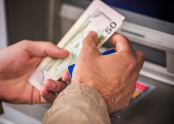 Hands with dollars at ATM for Social Security and some extra money for some eligible beneficiaries