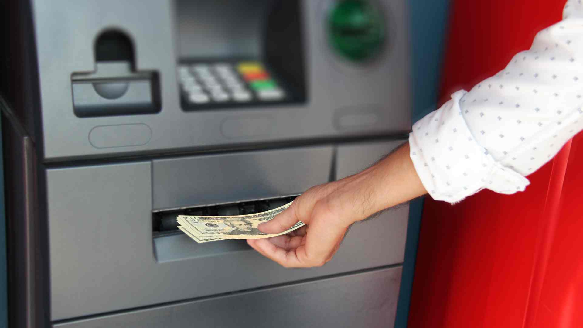 Hand taking dollars at ATM for Social Security checks and the upcoming SSDI payments in November