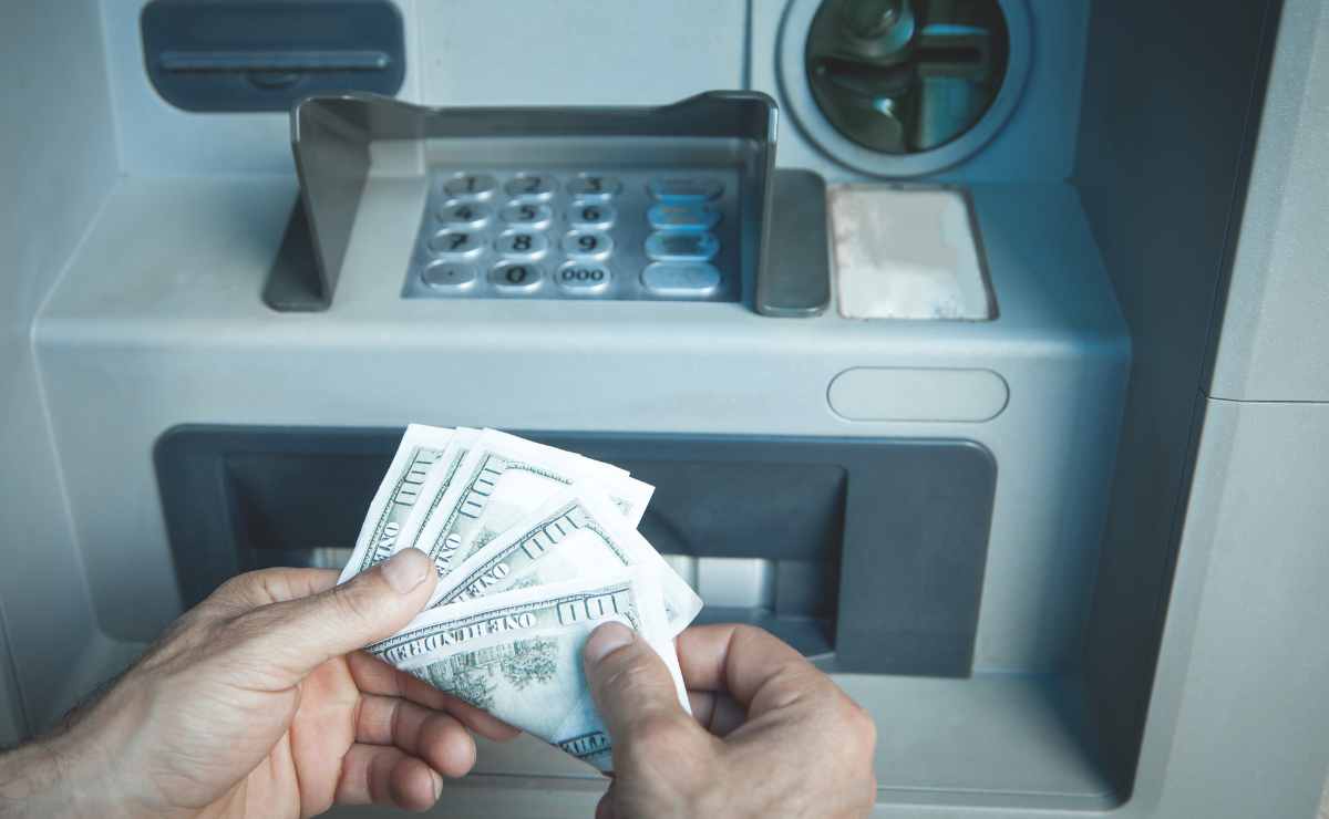Hand with dollars at ATM since Social Security payments coming soon in November