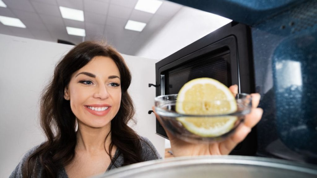 Mujer limpiando el microondas con un limón